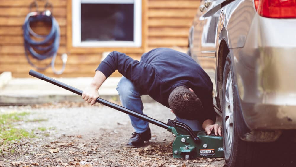 Closeup shot of a man repairing a car with a tool