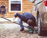 Closeup shot of a man repairing a car with a tool