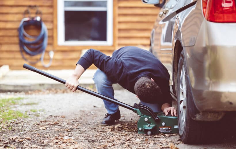 Closeup shot of a man repairing a car with a tool